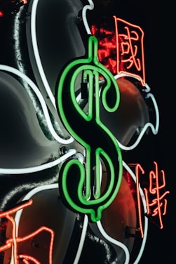 A large green neon dollar sign is prominently displayed, surrounded by white and red neon lines forming abstract shapes and Chinese characters.