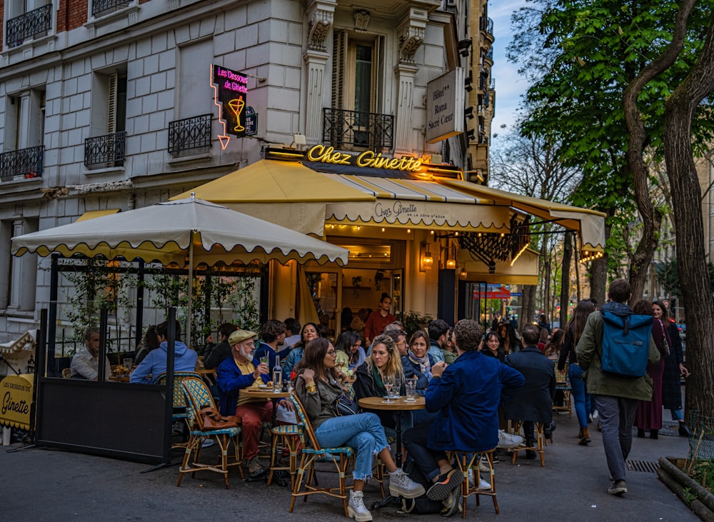 a group of people sitting at tables outside of a restaurant