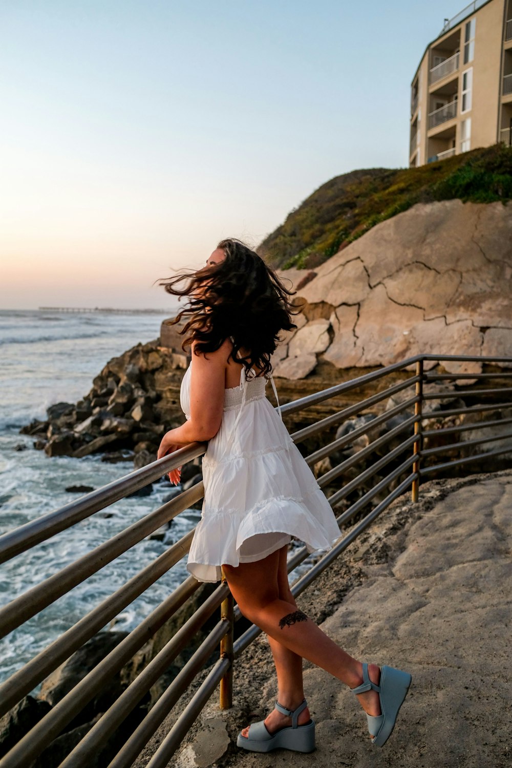 a woman sitting on a railing overlooking a body of water