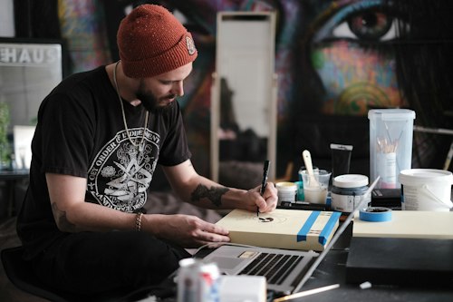 Tattooed artist sketching a custom design on paper at a desk