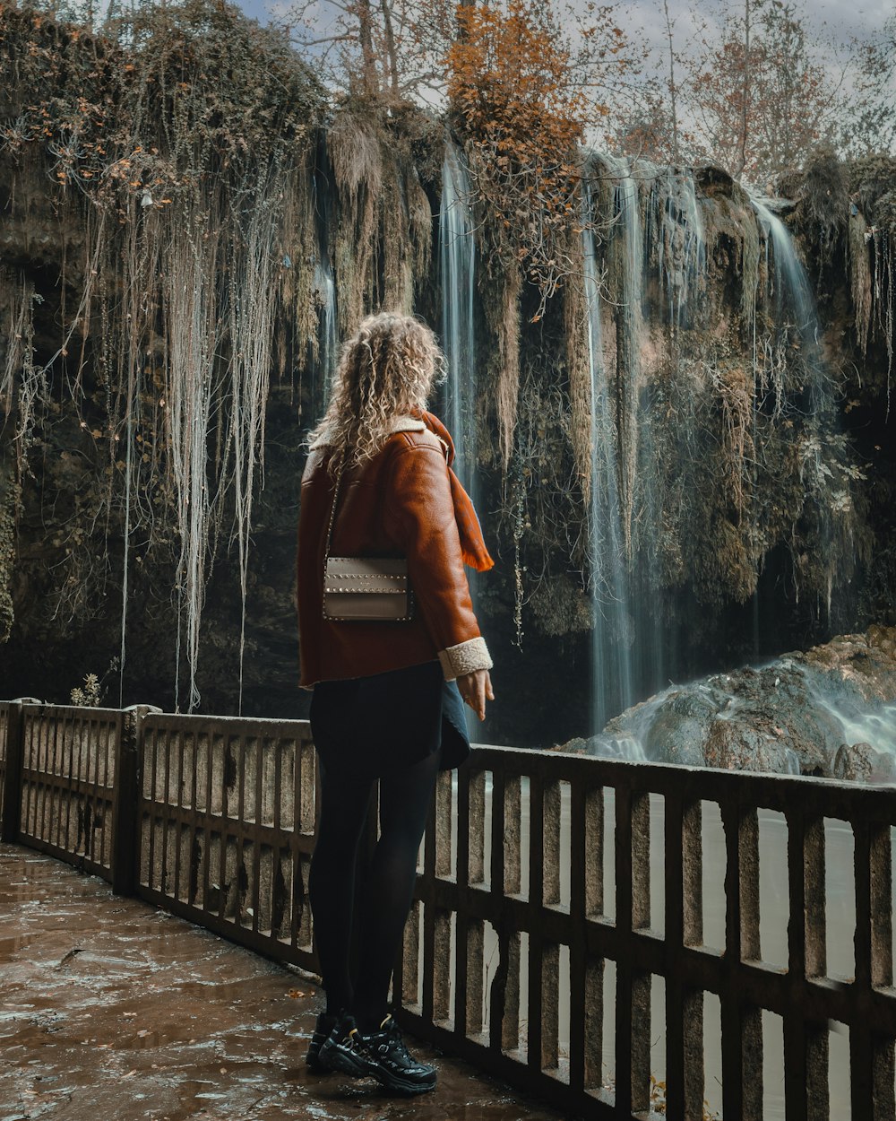 a person standing on a bridge looking at a waterfall