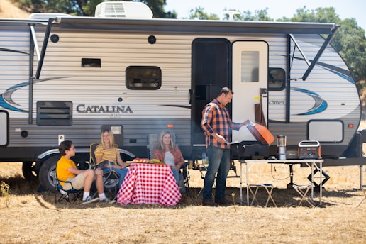 a group of people sitting outside a camper