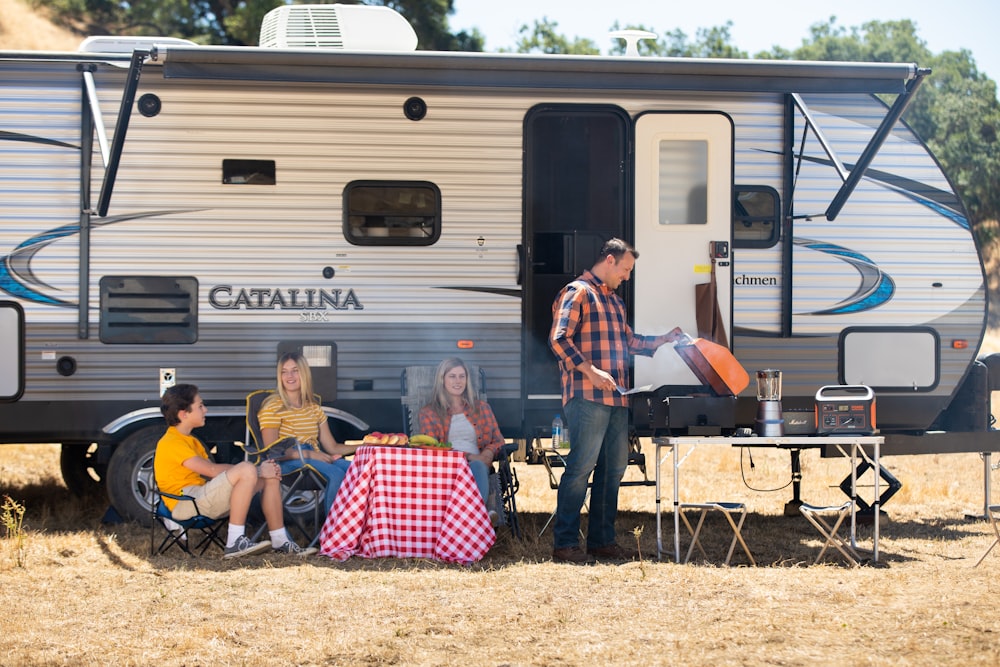 a group of people sitting outside a camper