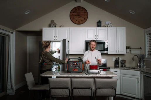 Technician repairing a refrigerator compressor inside a modern kitchen.