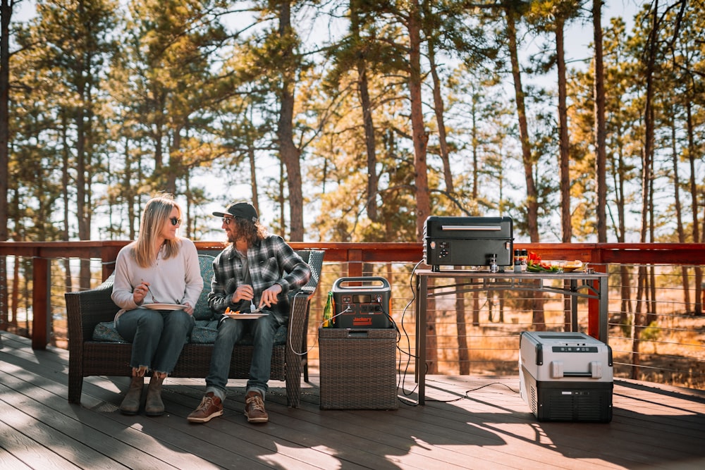 a man and woman sitting on a bench with a laptop and a speaker