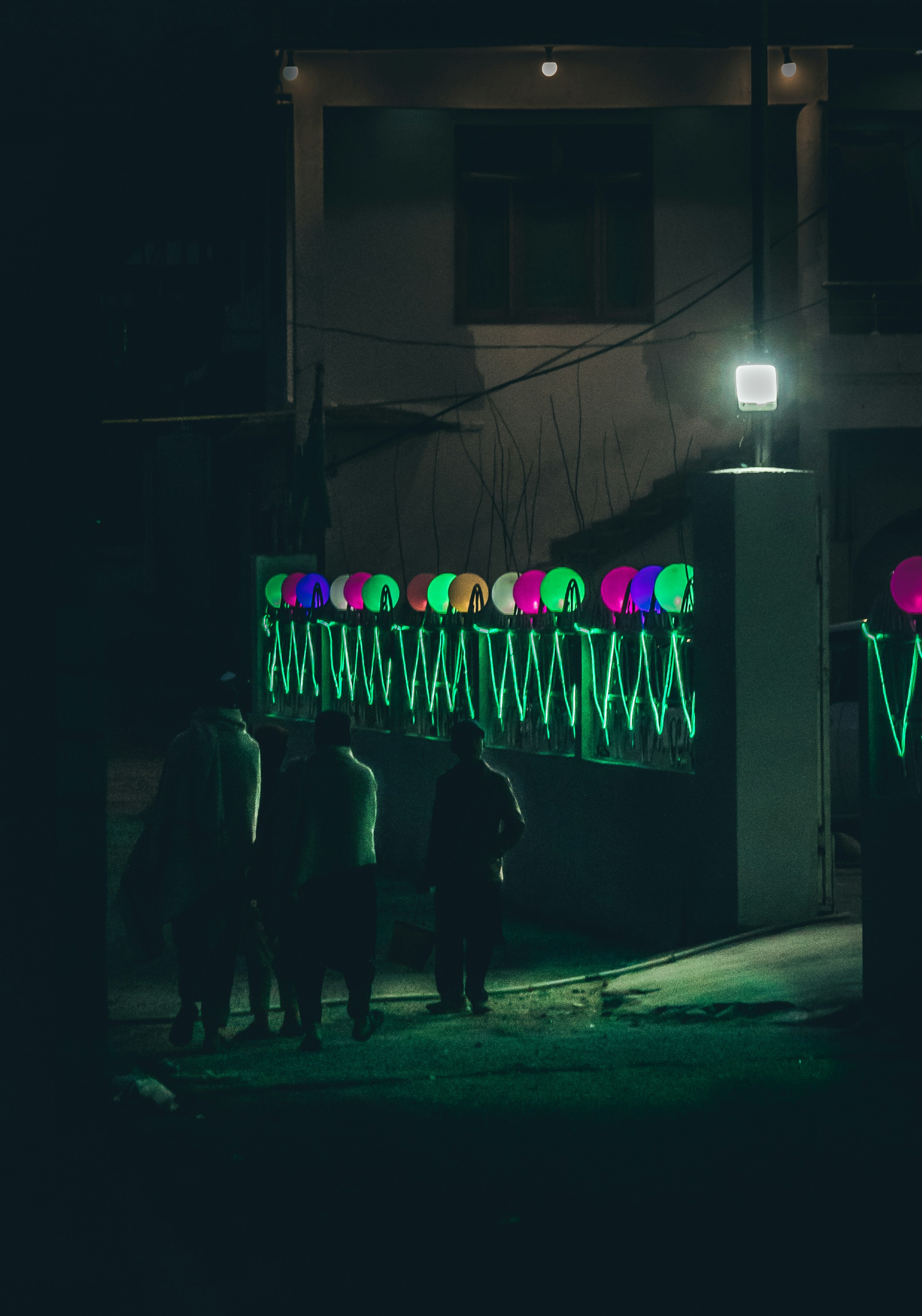 a group of people standing outside a building with neon lights