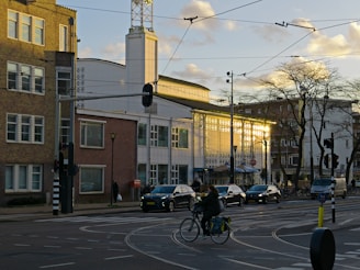 a person riding a bicycle on a street with cars and buildings