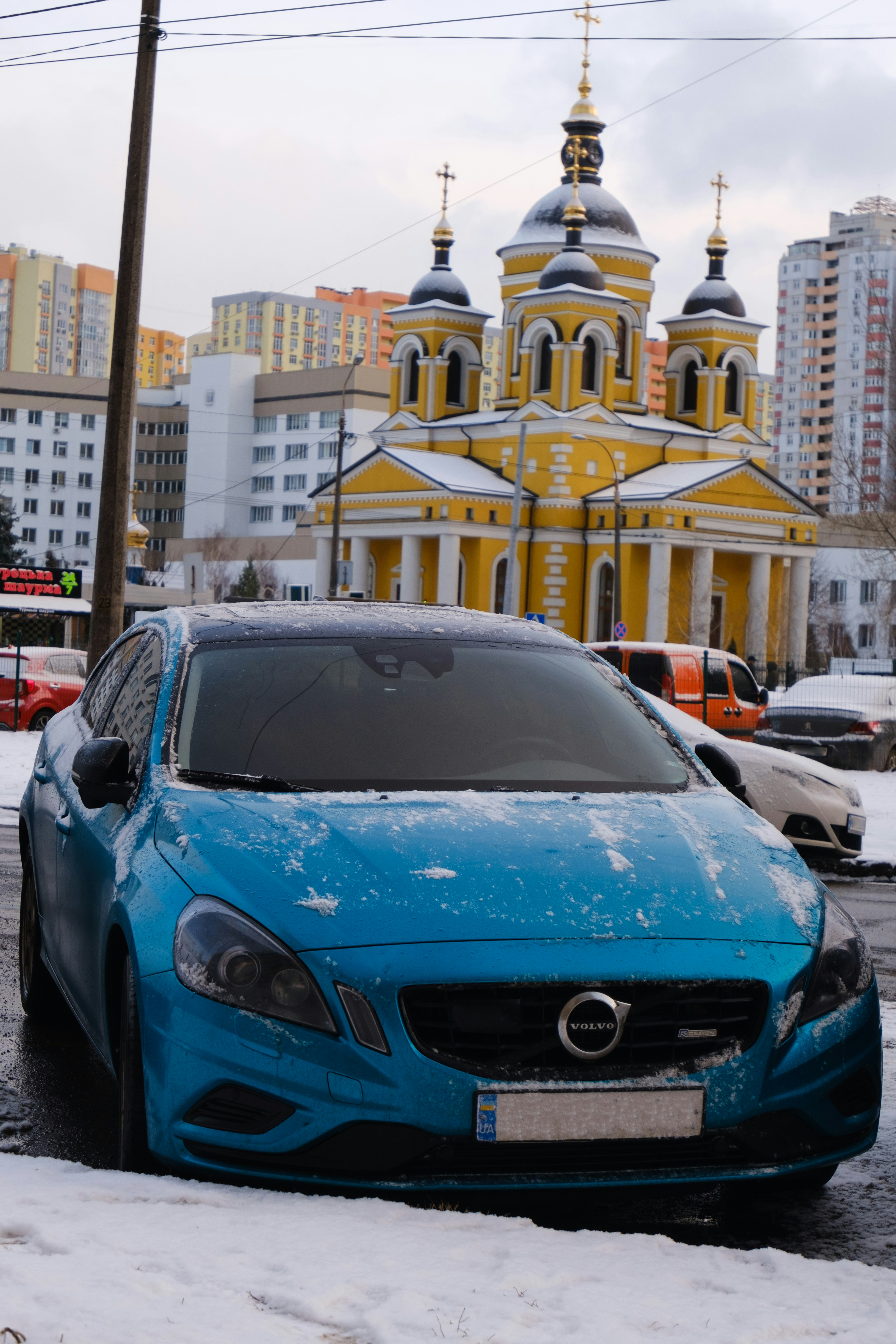 a blue car parked in front of a building with a gold roof