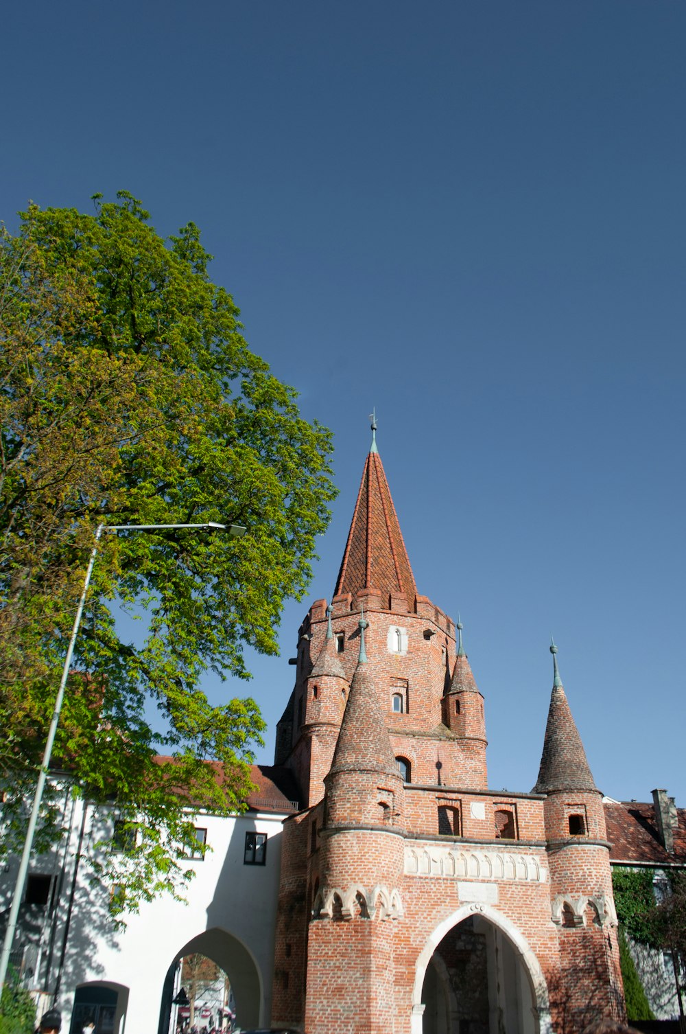 ein großes Backsteingebäude mit einem Kirchturm und einem Baum davor