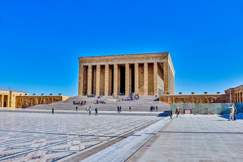 ein großes Gebäude mit Menschen, die mit Anıtkabir im Hintergrund herumlaufen