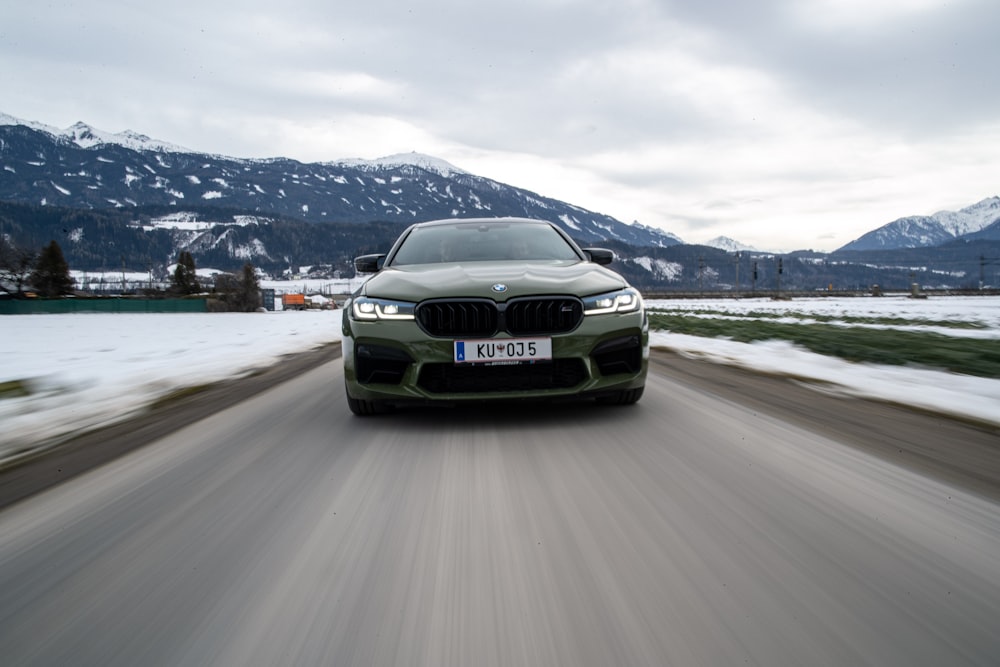 a car driving on a road with snow and mountains in the background