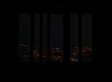 Evening cityscape view from a hotel room window with glowing lights.