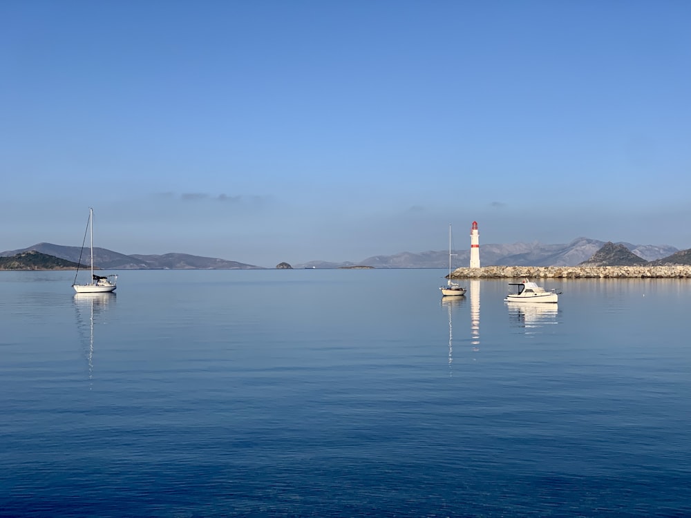 a body of water with boats in it and a lighthouse in the distance