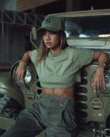 A model wearing a civilian cap against a graffiti wall, highlighting the blend of military heritage and streetwear style.