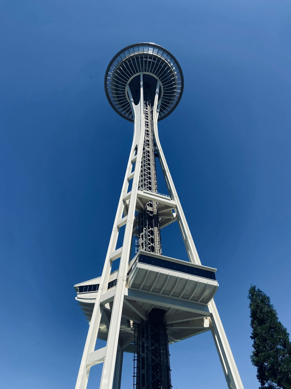 a tall tower with a round top with Space Needle in the background