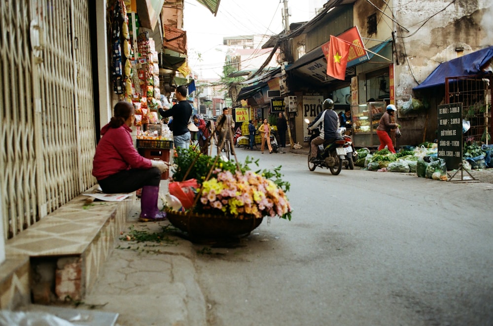 a person sitting on a bench next to a flower stand