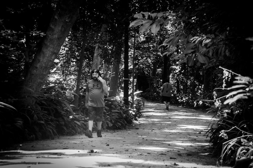 a couple of people walking down a path in the woods