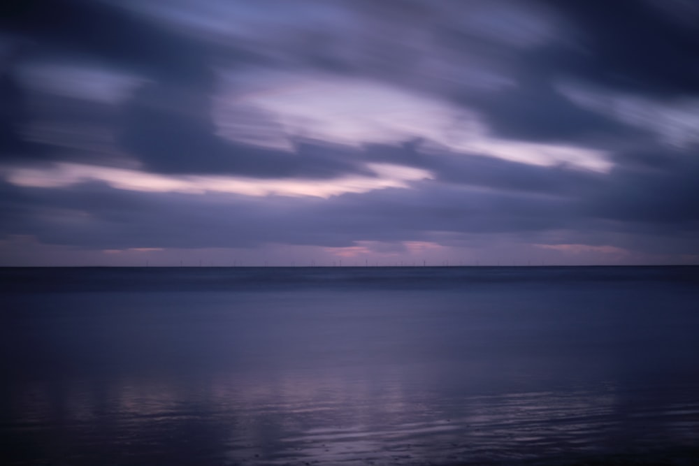 a body of water with clouds above it