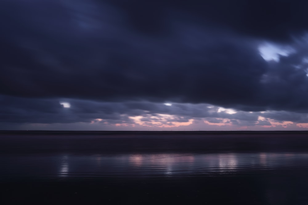 a body of water with a cloudy sky above it