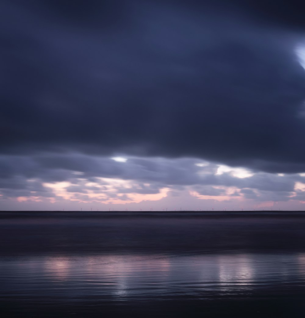 a body of water with clouds above it