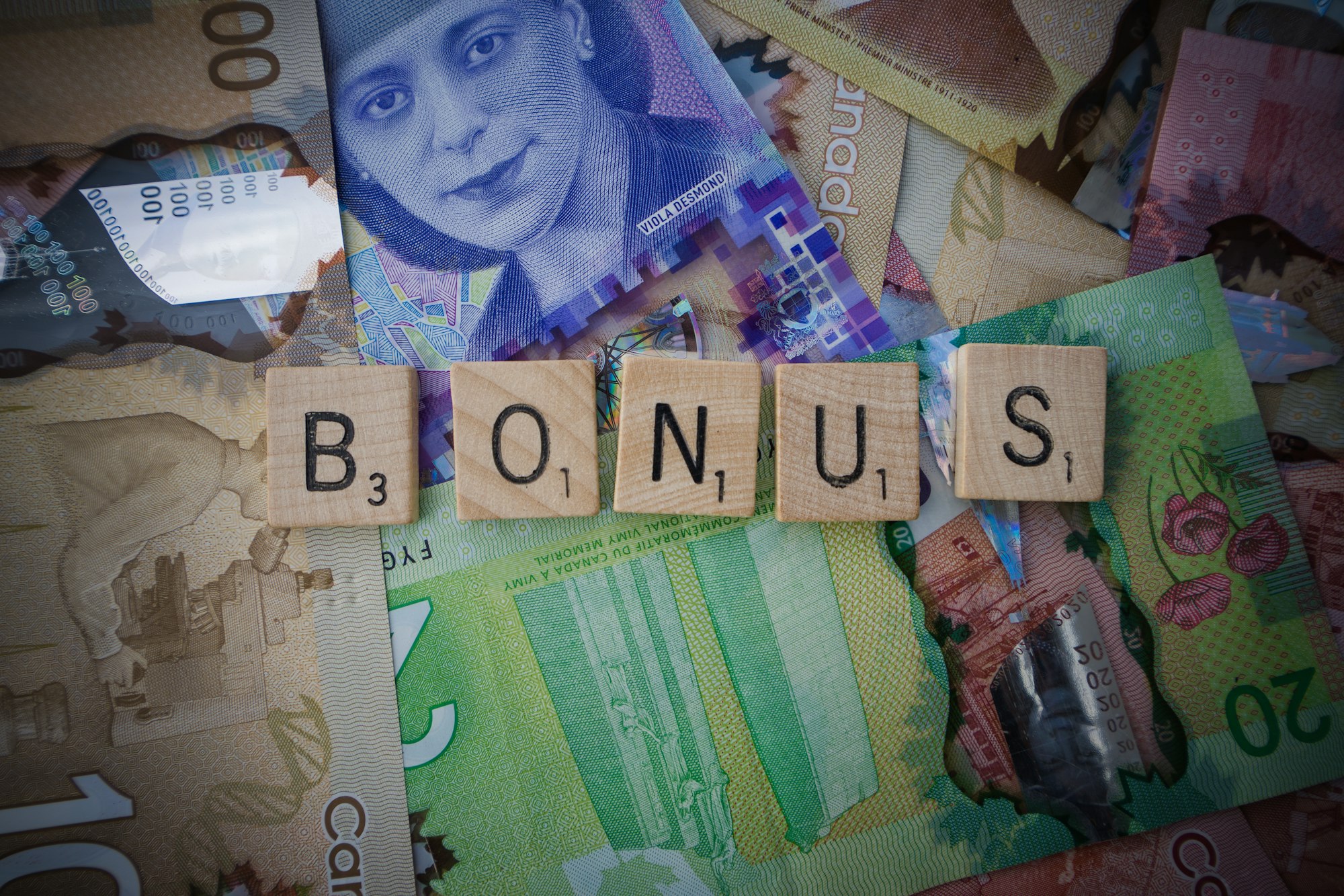 Scrabble letters spelling 'bonus' on Canadian bills
