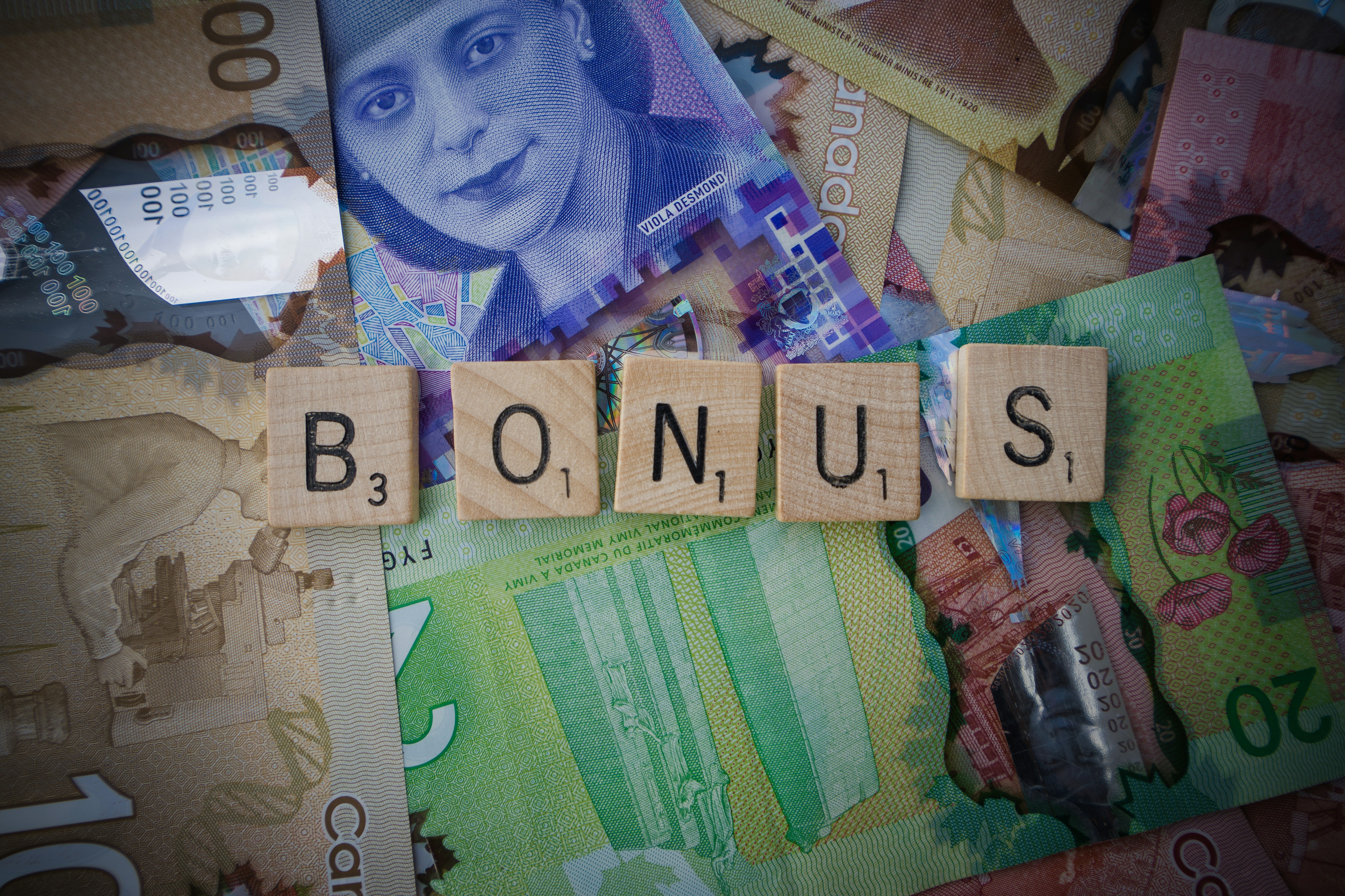 Scrabble letters spelling 'bonus' on Canadian bills
