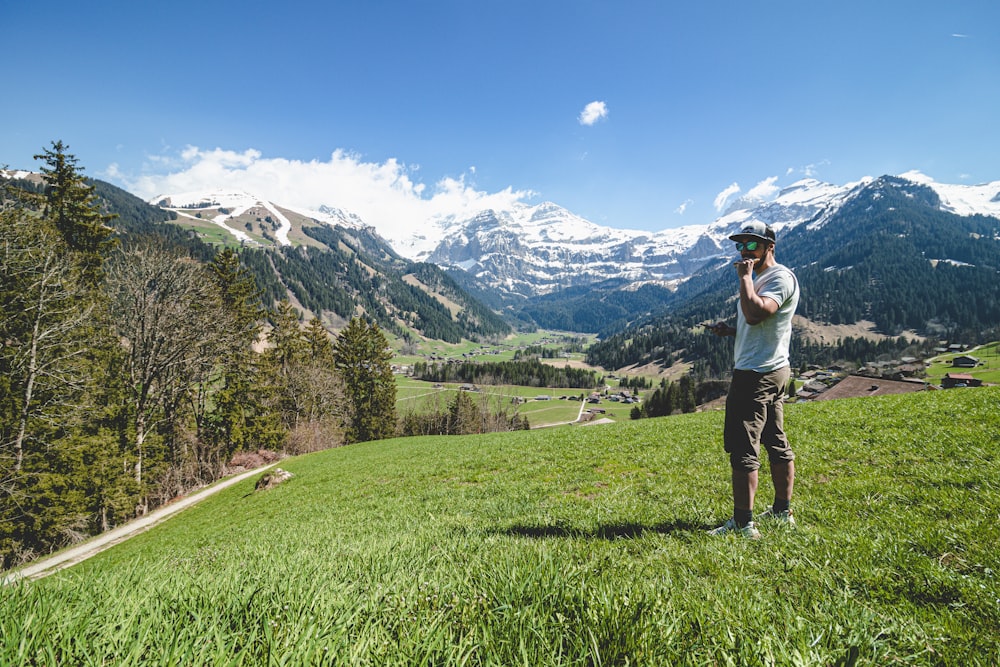 a person standing on a grassy hill with mountains in the background