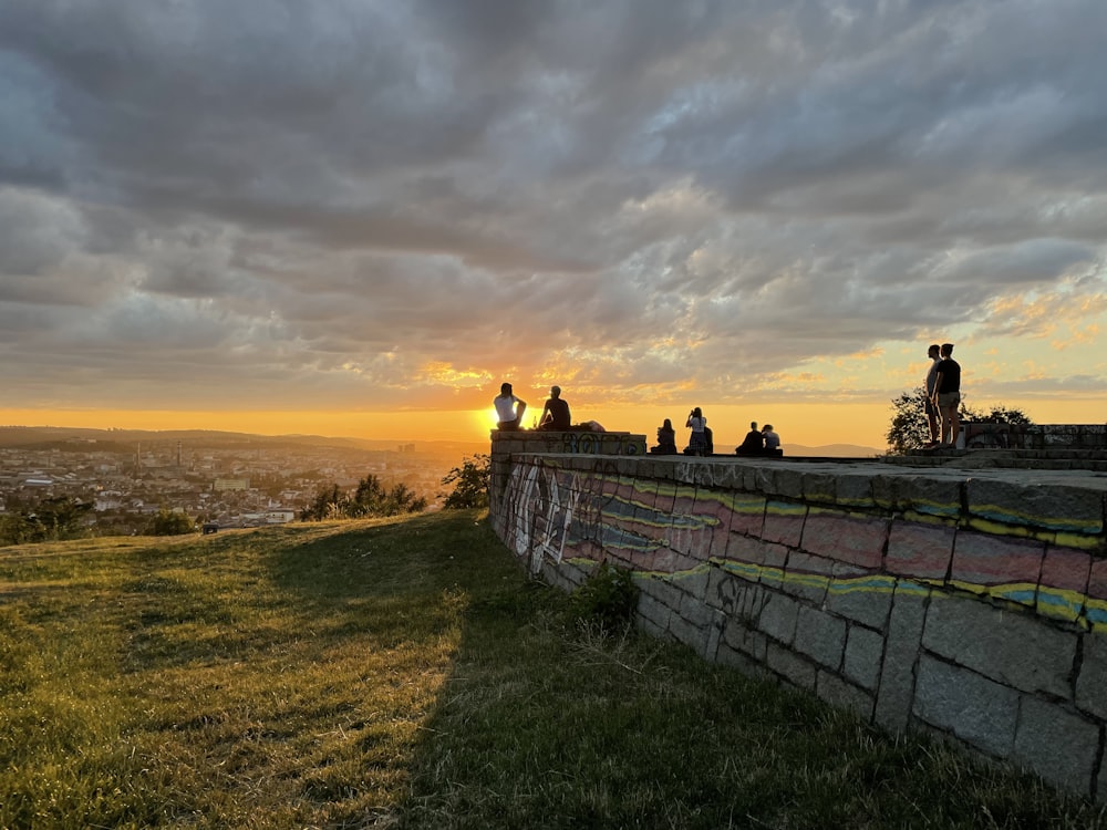 a group of people on a stone wall overlooking a city