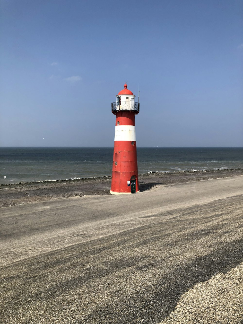 a red and white lighthouse on a beach