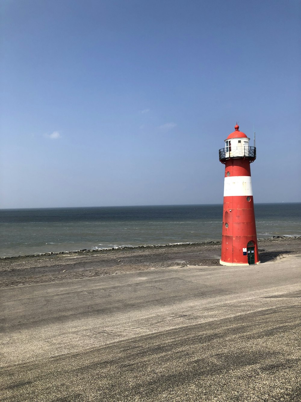 a red and white lighthouse on a beach