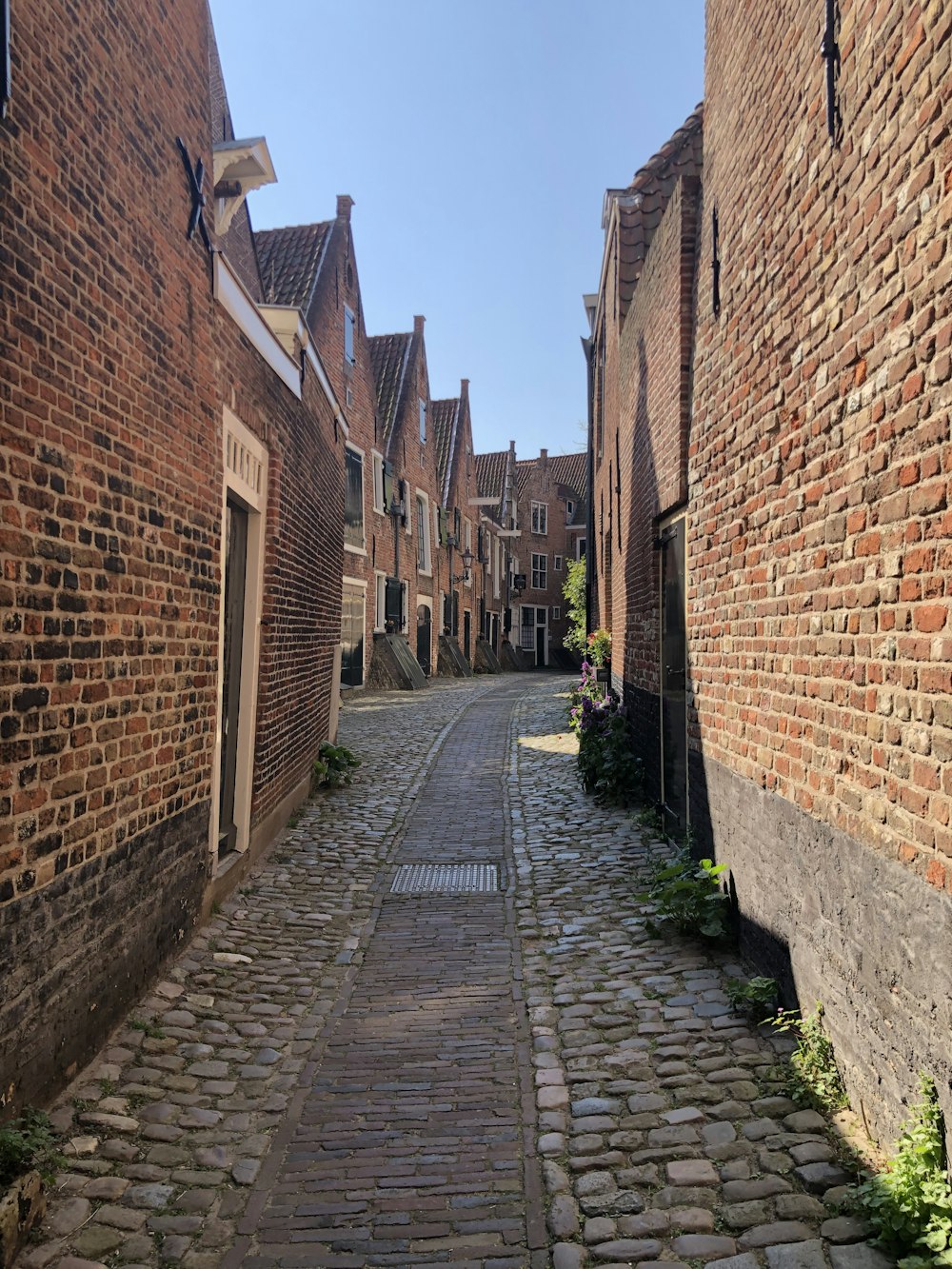 a cobblestone street between brick buildings