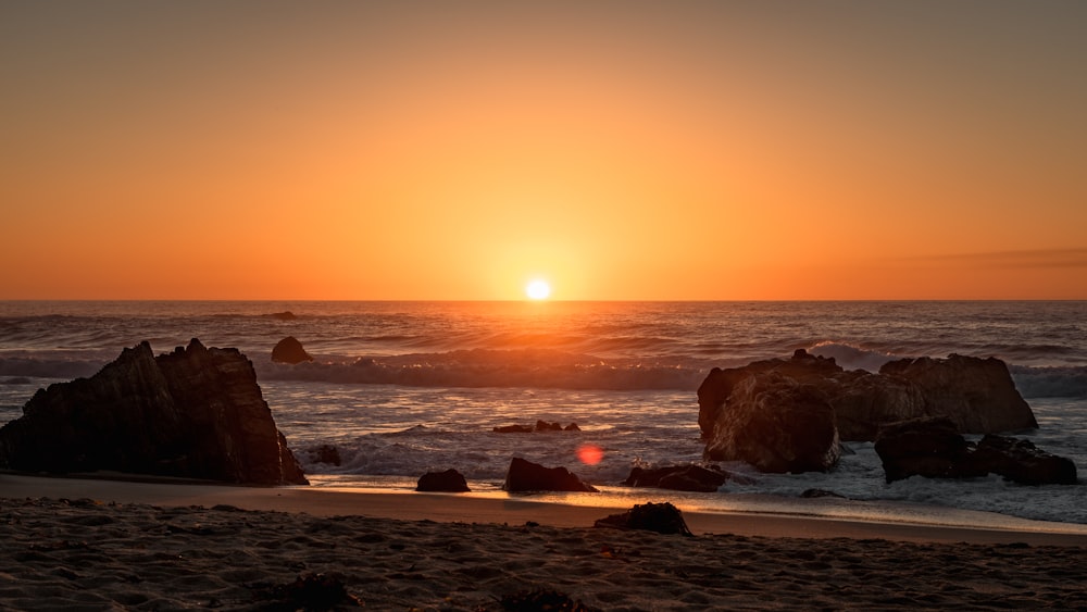 a sunset over a rocky beach next to the ocean