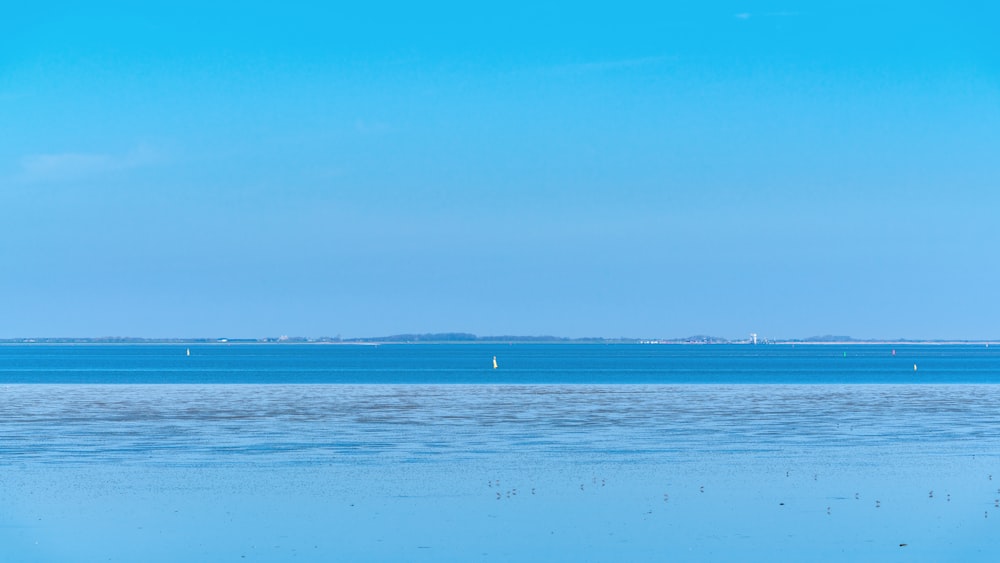 a body of water with snow on the ground and blue sky