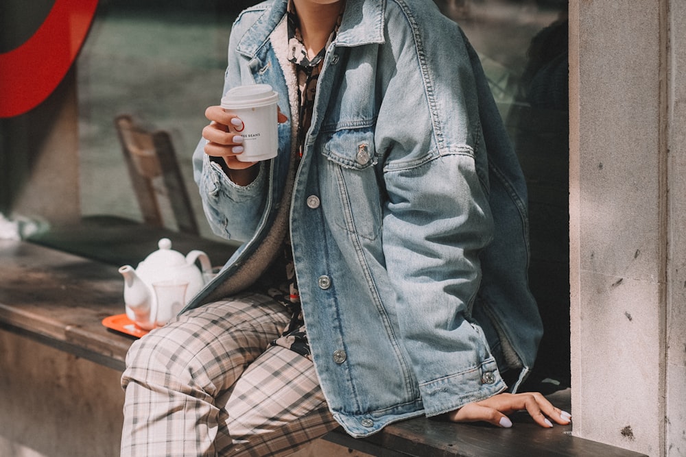 a person sitting on a bench holding a cup