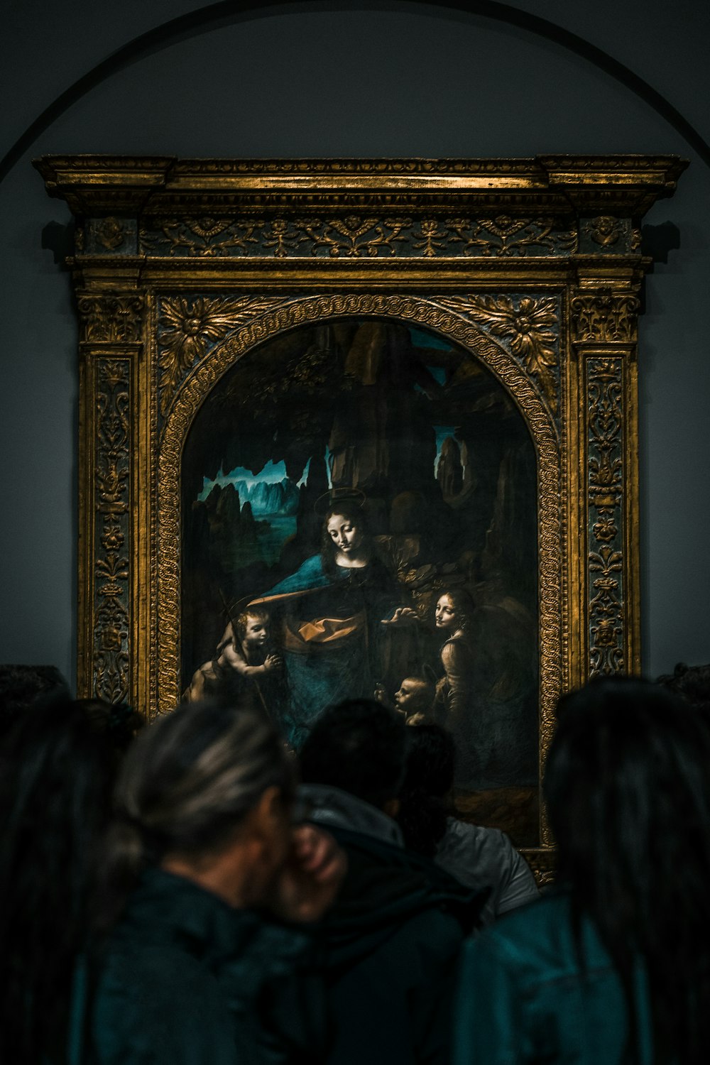 a group of people looking at a painting on a wall