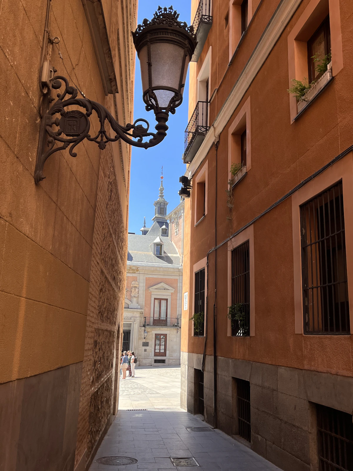 A narrow ochre lane with an ornate street lamp in historic Madrid