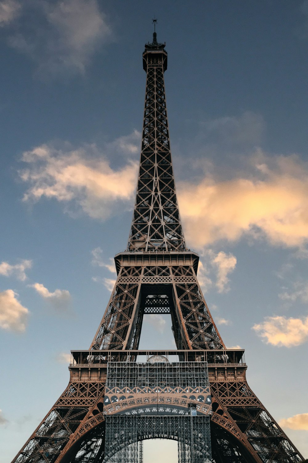 uma torre de metal alta com a Torre Eiffel ao fundo