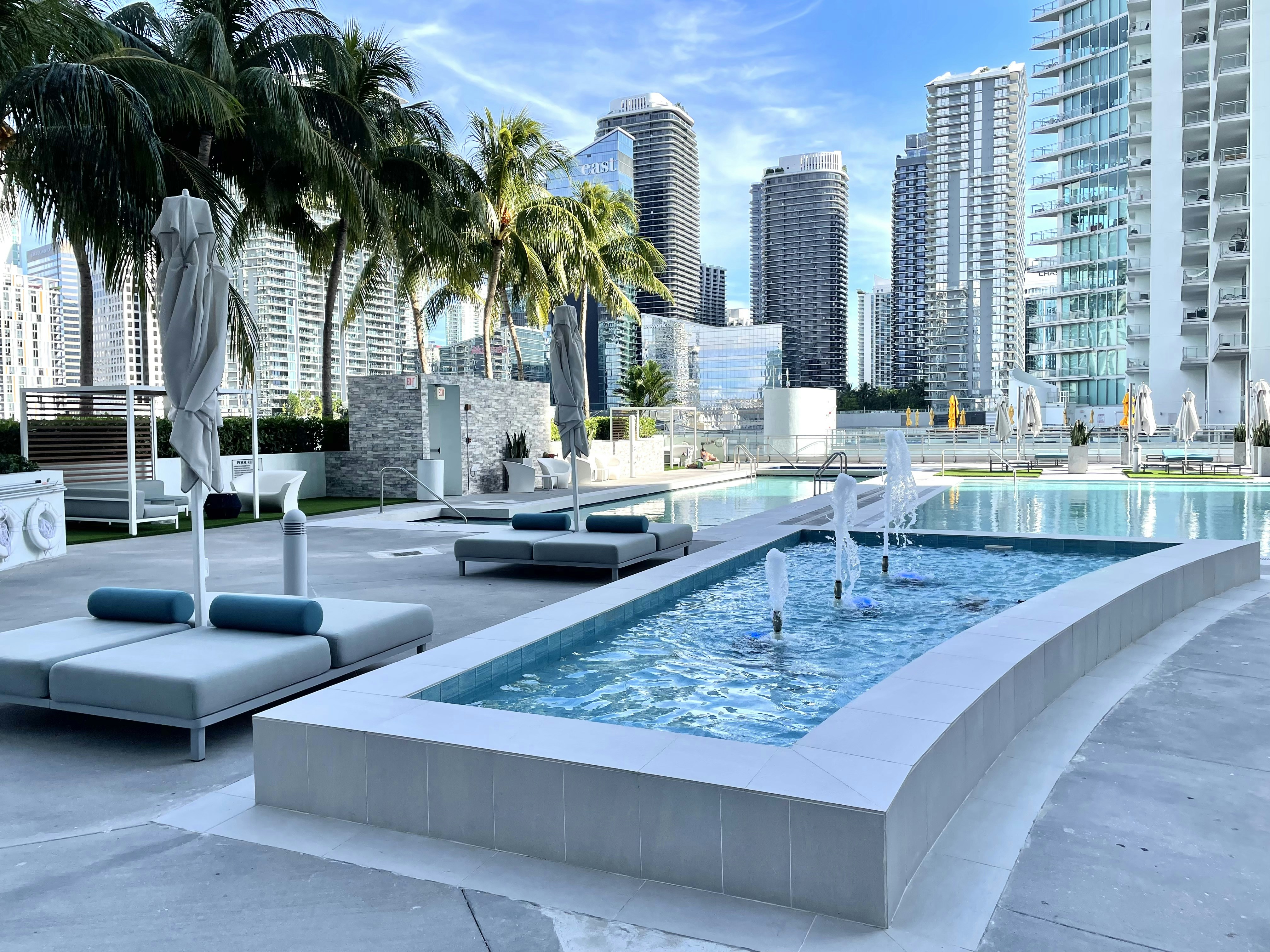 a pool with a fountain in it and buildings in the background