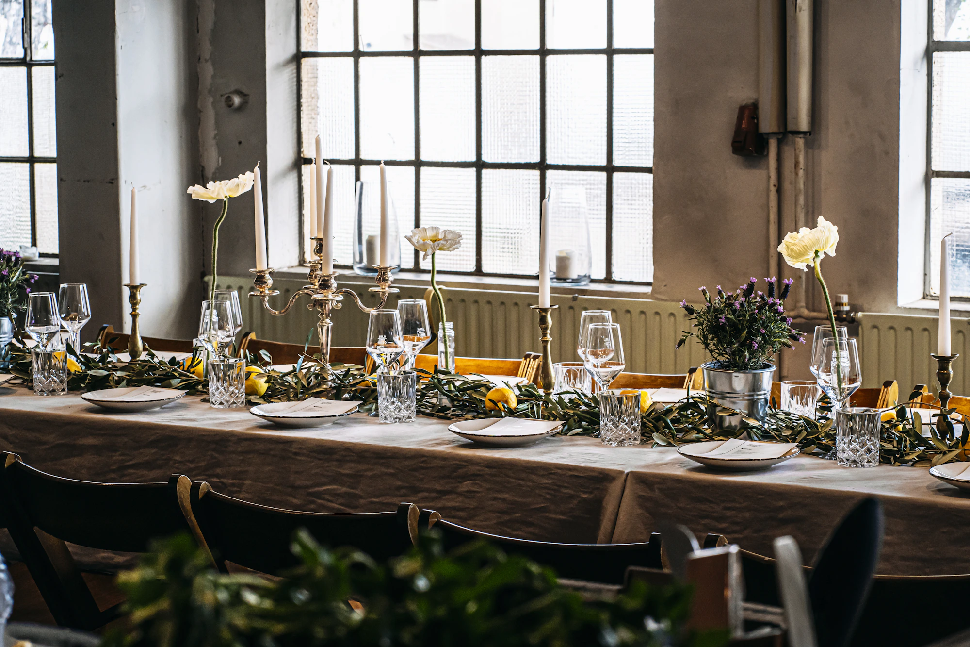 Wide dining table arranged with plates, glasses and refined tableware