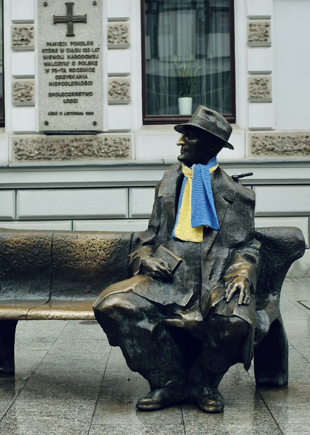 eine Statue einer Person, die auf einer Bank sitzt