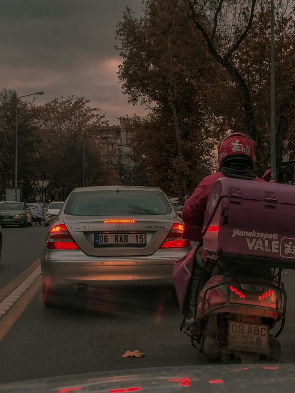 a person on a motorcycle in the street with a car behind them