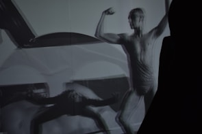 Side view of a focused athlete mid-squat, shadows emphasizing muscle definition against a dark background.