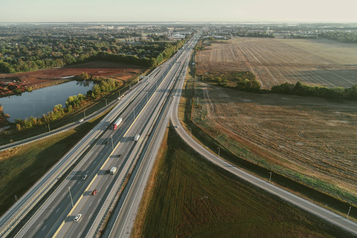 Aerial view of a divided highway on a fill embankment cutting through farmland — the rainfall-erosion-prone slope face Texas Tuff Rock Bags armor against rill and gully formation