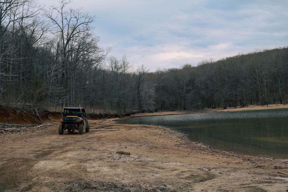 a tractor on a dirt road by a lake with trees