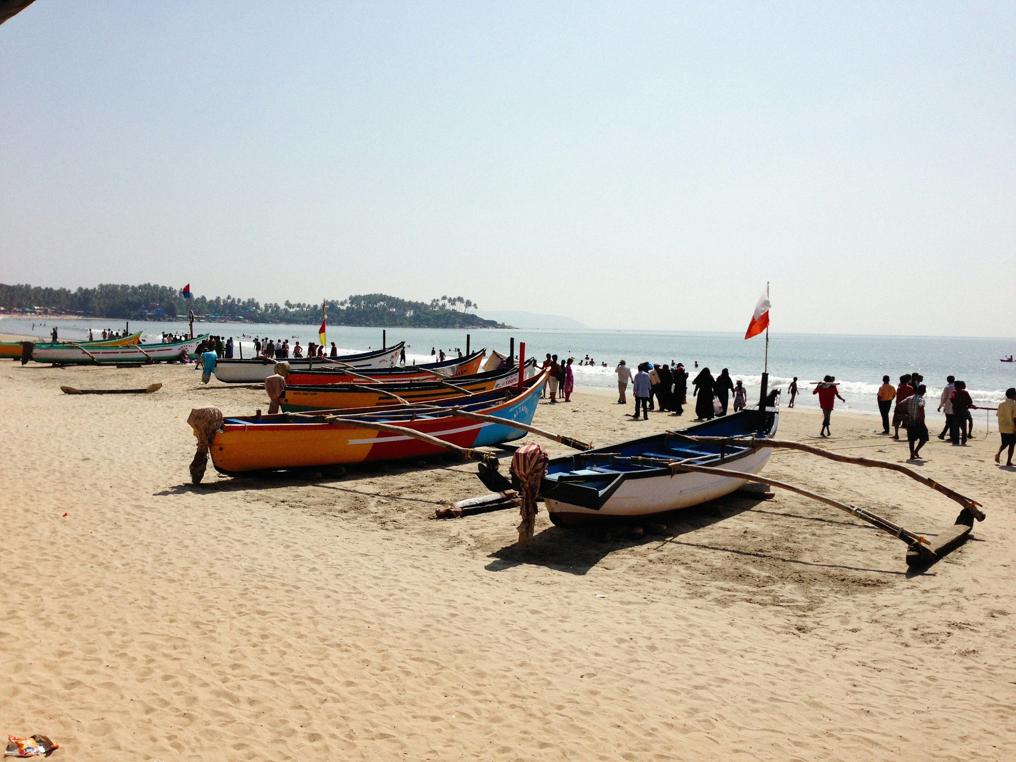 Alibaug beach with fishing boats and green palm trees along the shoreline