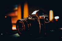 Close-up of a film camera lens reflecting a vibrant social media campaign scene in monochrome tones.