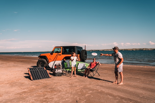 a man throwing a frisbee at a woman on a beach with a Jackery Panel Kit