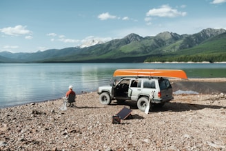 a person sitting on a chair next to a truck on a rocky beach using solar power