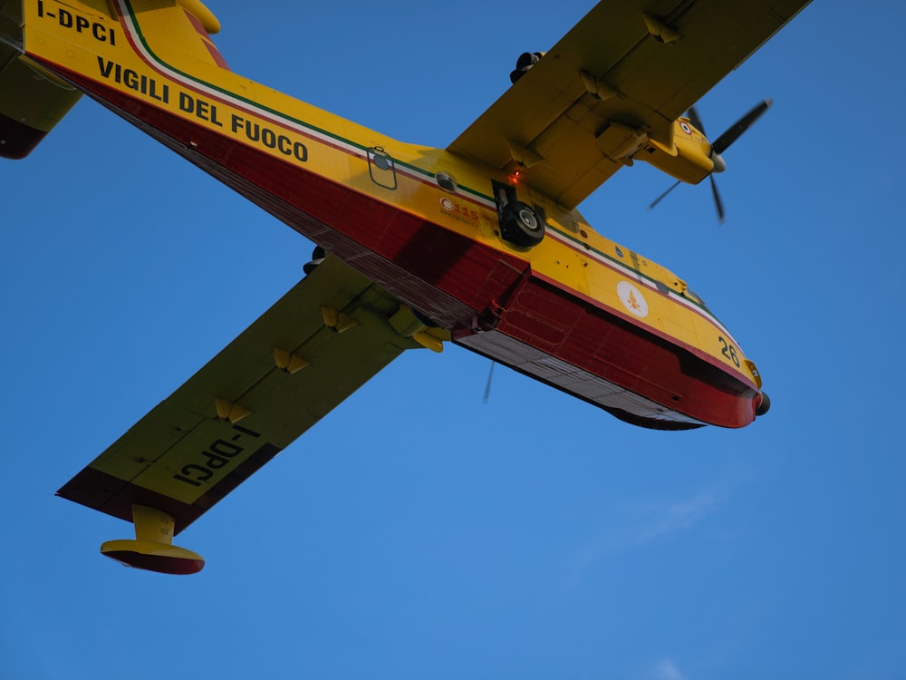 a yellow and red airplane in the sky