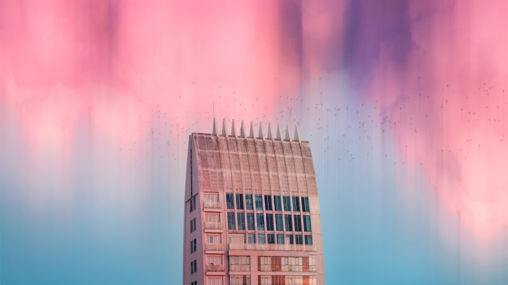 a tall building with a pink and blue sky